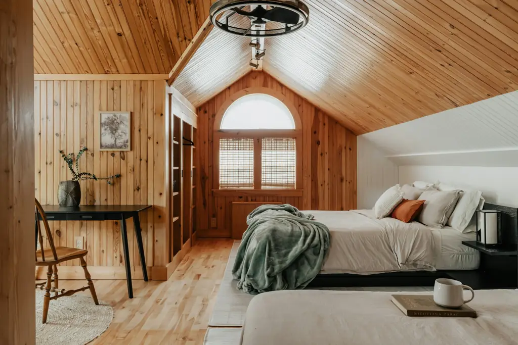 Dormitorio de cabaña en madera clara con luz de ventana